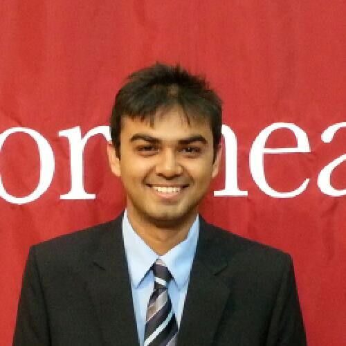 A man in suit and tie standing next to a red wall.