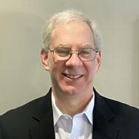 A man in a suit and tie smiling for the camera.