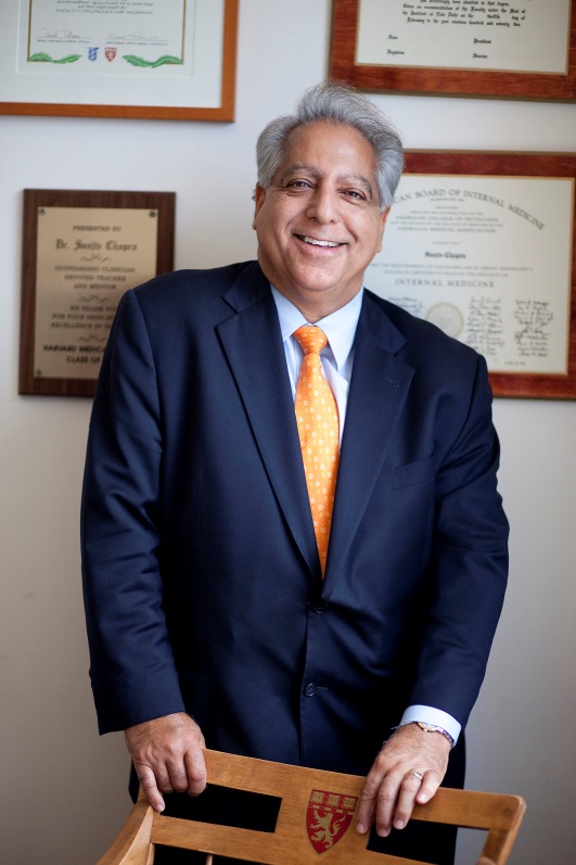 A man in a suit and tie standing next to two framed certificates.