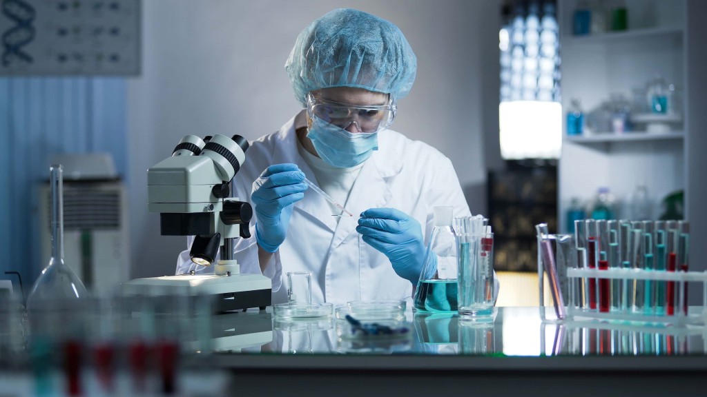 A person in lab coat and mask working with equipment.